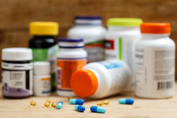 garrafas de remédios e comprimidos em mesa de madeira - vitamin pill nutritional supplement capsule antioxidant - fotografias e filmes do acervo