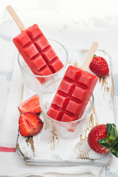 istock Strawberry ice cream popsicles on white stone table 682884738