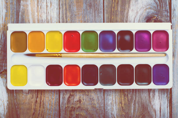 istock Watercolor paints set and brush on wooden table 682893614