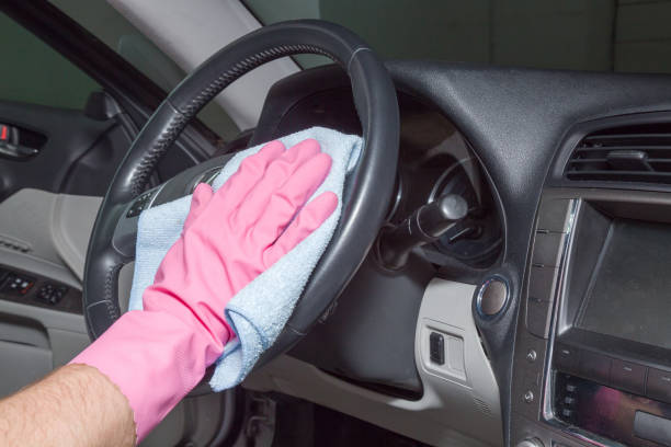 istock Hand in rubber protective glove with rag cleaning a dusty car steering wheels. Early spring cleaning or regular clean up. 682897140