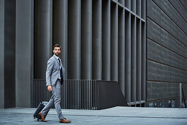 confident businessman with bag against building - mode bcbg photos et images de collection