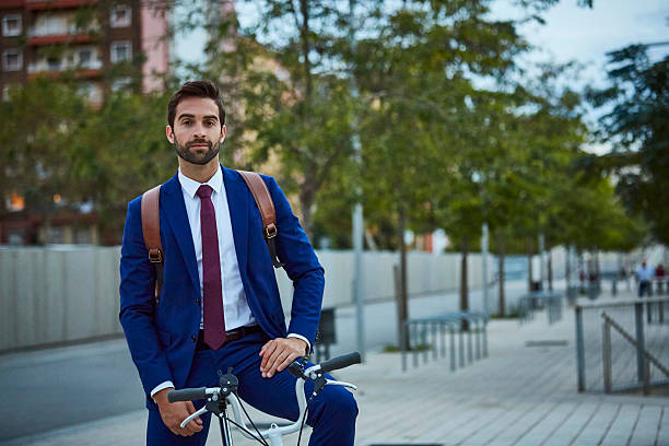 male executive riding bicycle on sidewalk - short cycle ストックフォトと画像