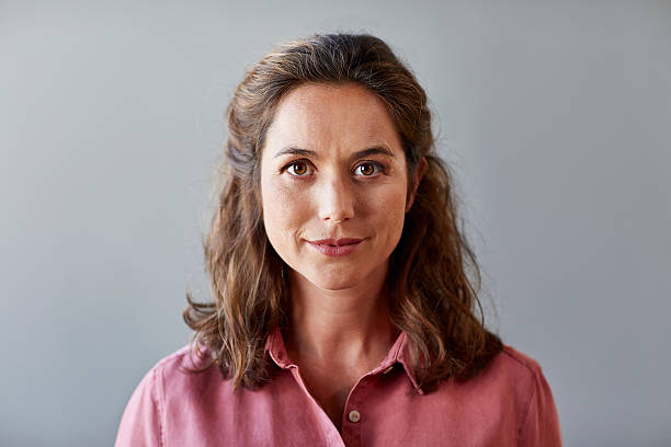 confident businesswoman over gray background - gesichtsausdruck fotos stock-fotos und bilder