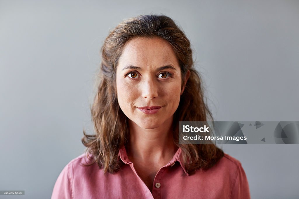 Confident businesswoman over gray background Portrait of confident businesswoman. Beautiful female professional is wearing shirt. She is against gray background. Women Stock Photo