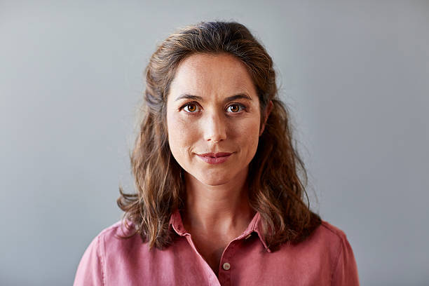 Confident businesswoman over gray background Portrait of confident businesswoman. Beautiful female professional is wearing shirt. She is against gray background. looking at camera stock pictures, royalty-free photos & images