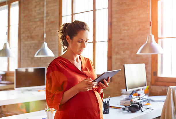 pregnant businesswoman using tablet pc in office - one person women human pregnancy beautiful photos et images de collection