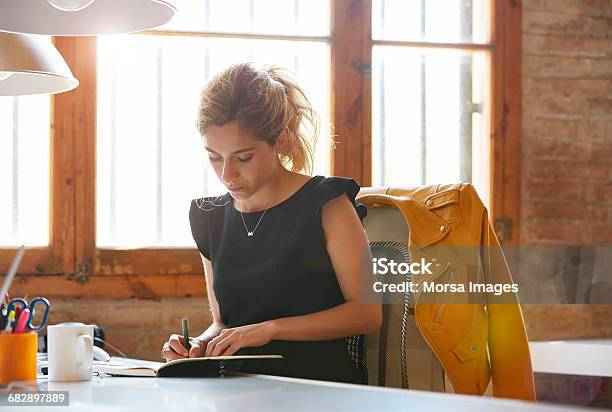 Businesswoman Writing In Book At Desk Stock Photo - Download Image Now - Writing - Activity, Women, Working