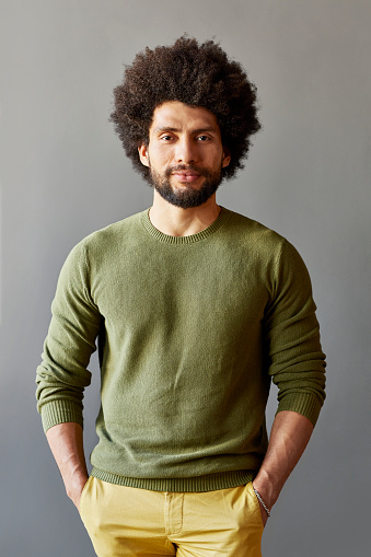 Portrait of confident businessman with hands in pockets. Smart male professional is wearing casuals. He is standing over gray background.