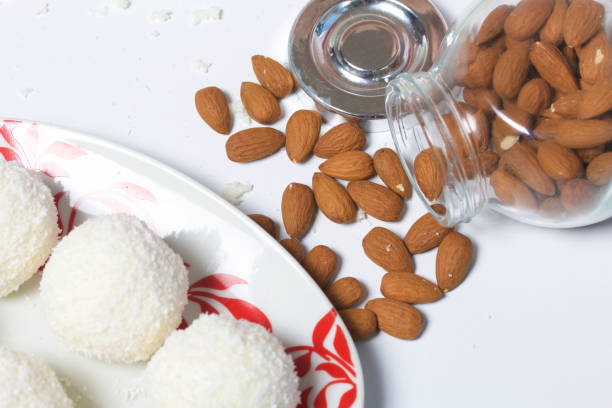 Preparation of Raffaello sweets at home. Ready-made sweets lie on a plate. On a background of a jar with scattered almonds.