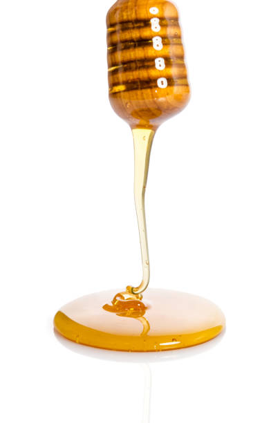 miele gocciolante da un cenato di miele di legno isolato su sfondo bianco - honey purity raw pollination foto e immagini stock