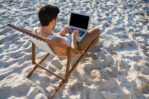 istock High angle view of man using laptop at beach 682904822