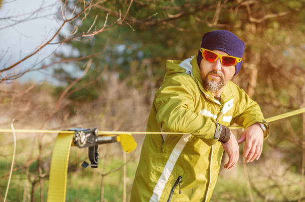 istock Close-up portrait of a man adjusting slacklining equipment before performing crazy slacklining tricks and walking on slacklin in a park in nature 682912596