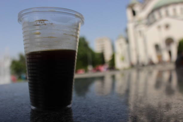 One Disposable glass coffee cup on marble seat outside in a public park at sunny day, after rain,  in front of the Serbian Orthodox Temple Saint Sava in Belgrade