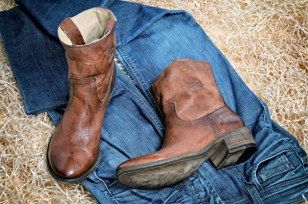 istock Leather cowboy boots and jeans on straw 682924632