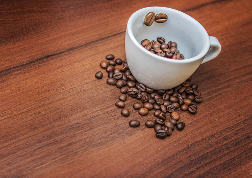 A light cup on a tree filled with coffee beans. Coffee beans in a cup. Coffee on the tree.