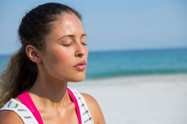istock Young woman with eyes closed meditating at beach 682936804