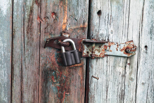 istock Closed old rusty padlock on a green wooden door 682940224