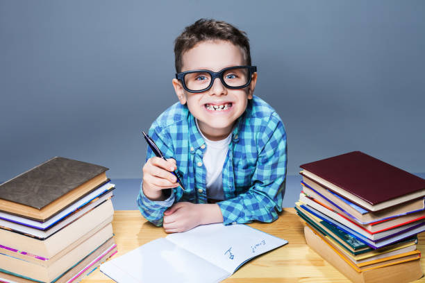 istock Smiling kid in glasses doing homework at the desk 682946556