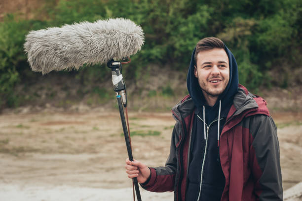 hinter den kulissen. sound-boom operator halten mikrofon fisher im freien - recorded outdoors stock-fotos und bilder