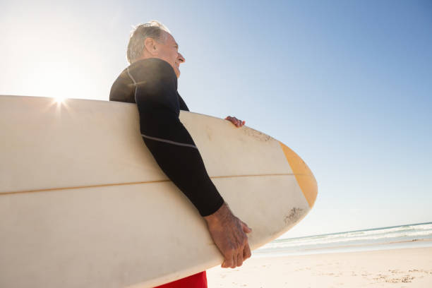istock Low angle view of man carrying surboard while standing at beach 682964706