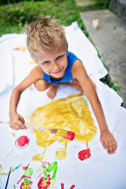 istock Little boy painting outdoors on big paper 682965376