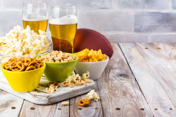 Beer, snacks and rugby ball on wooden table