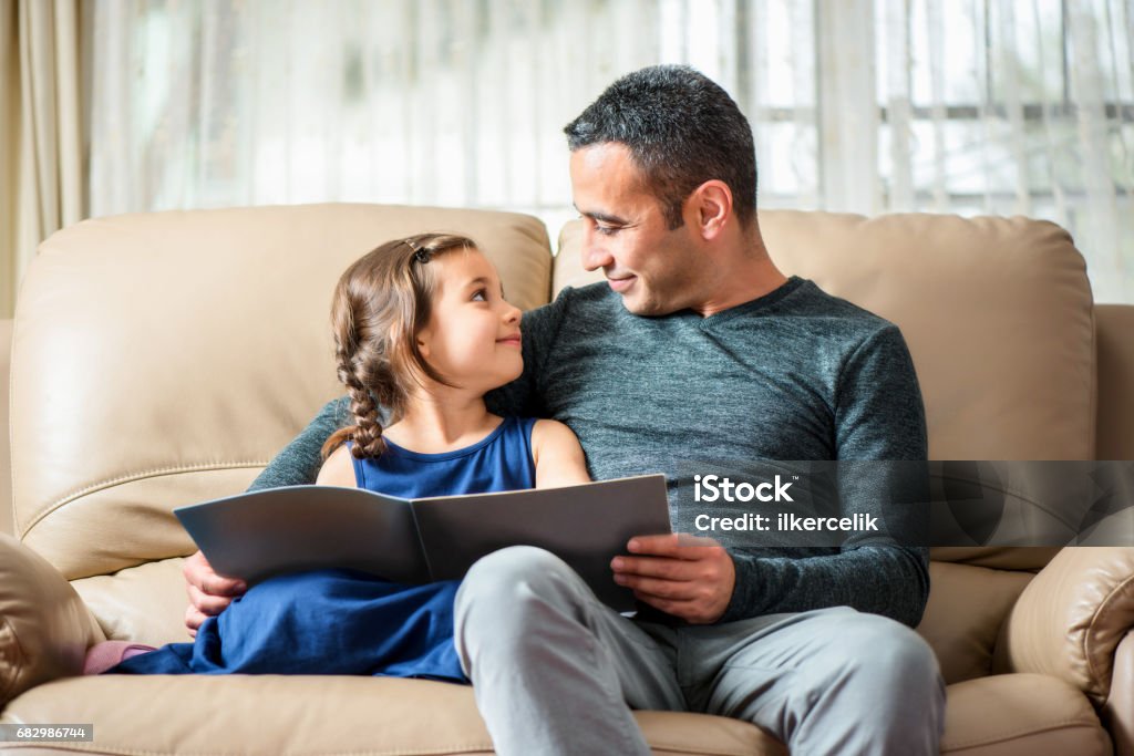 Little Girl And Father Reading Book Little girl and father are enjoying reading book together Baby - Human Age Stock Photo