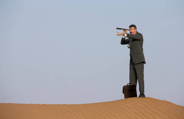 istock man in a suit in a desert with a spyglass 682999880