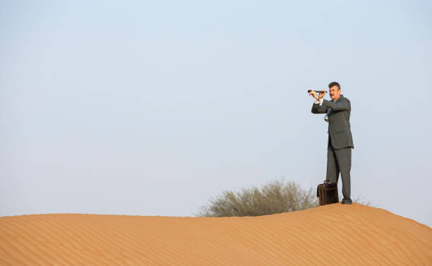istock man in a suit in a desert with a spyglass 683000124