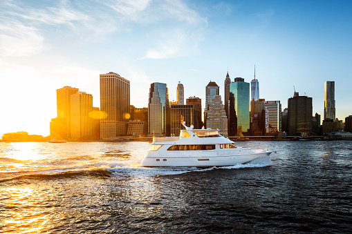 A yacht motors up the East River with the Manhattan skyline in the background.