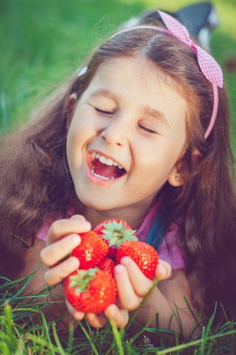 Child with strawberry outdoors in summer