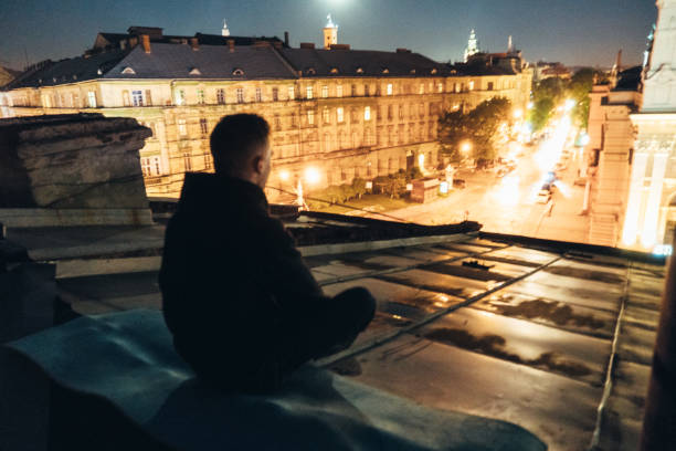 istock Man sitting on the roof at night 683024914
