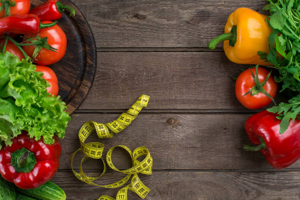 istock Vegetables and in measure tape in diet on wooden background. Top view 683034800