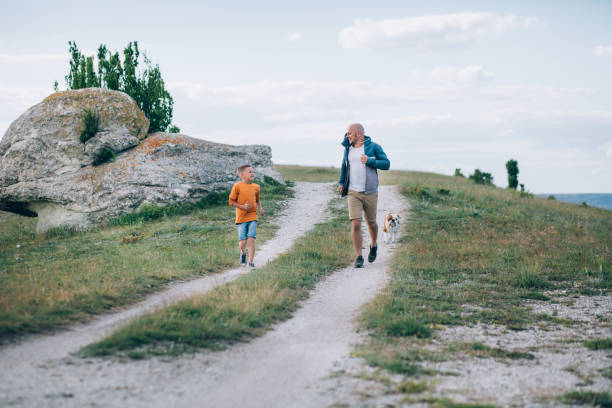 istock Dad and son running on the field with the dog 683035308
