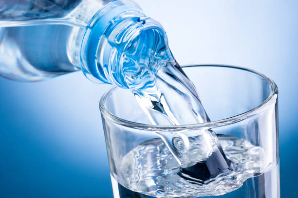 istock Close-up pouring water from bottle into glass on blue background 683036028
