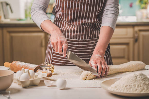 istock Close-up view of two woman's hands cut knife dough 683038454