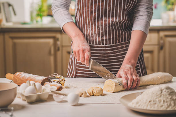 istock Close-up view of two woman's hands cut knife dough 683038508