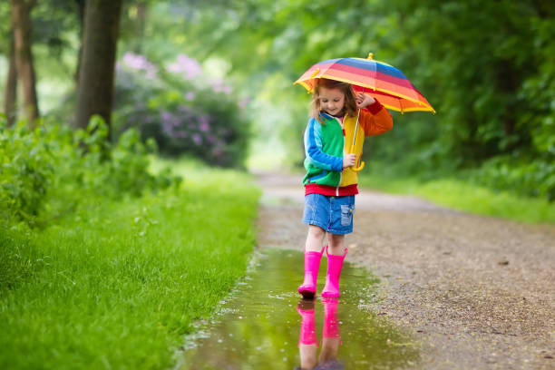 istock Child playing in the rain with umbrella 683041392