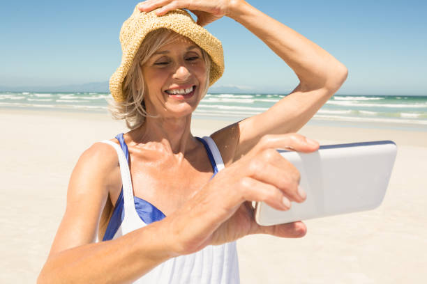 istock Woman using smart phone while standing at beach against clear sky 683041718