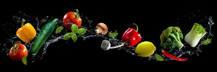 Vegetables on black background with water splash