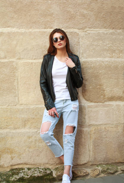 istock Young woman in retro rock style near stone wall 683048114