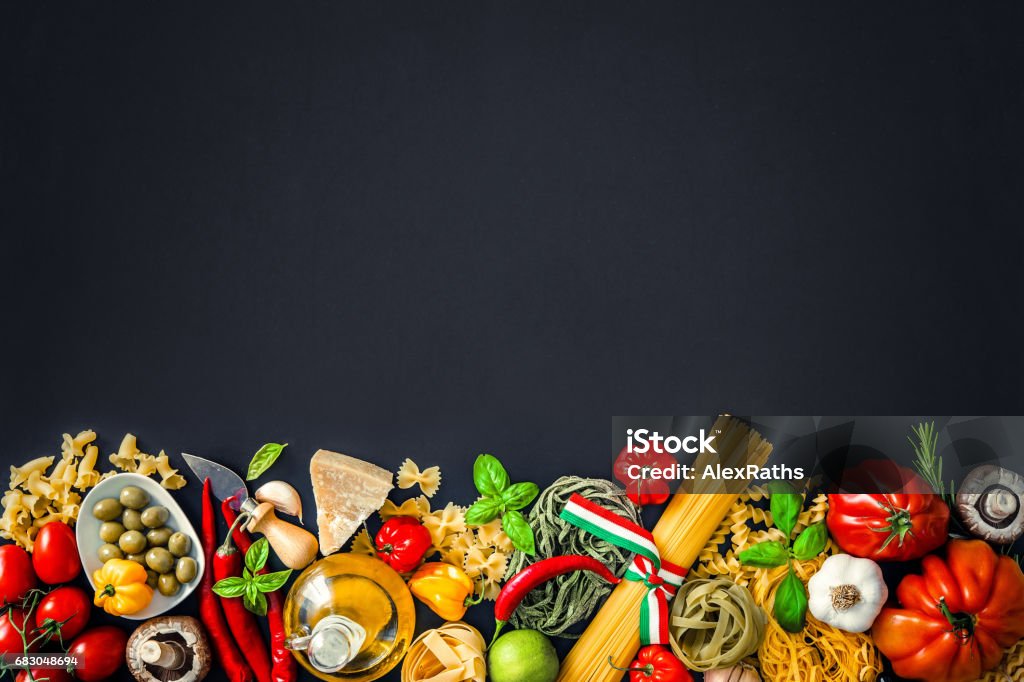 Italian food ingredients on slate background Italian cuisine. Vegetables, oil, spices and pasta on dark background Italian Food Stock Photo