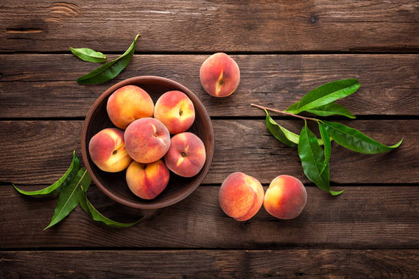 istock Fresh juicy peaches with leaves on dark wooden rustic background 683058024