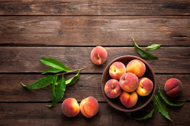 istock Fresh juicy peaches with leaves on dark wooden rustic background 683058054