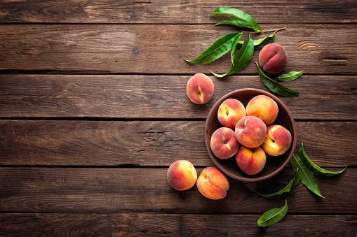 Fresh juicy peaches with leaves on dark wooden rustic background