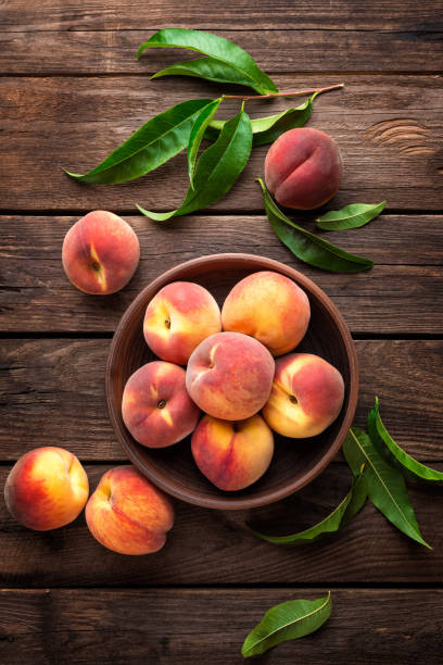 istock Fresh juicy peaches with leaves on dark wooden rustic background 683060216