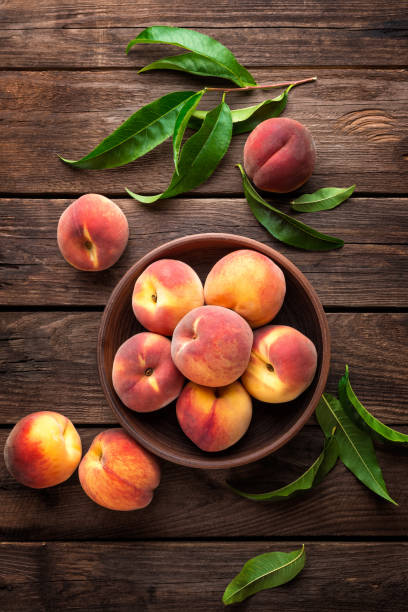 свежие сочные персики с листьями на темном деревянном деревенском фоне - nectarine peach red market стоковые фото и изображения