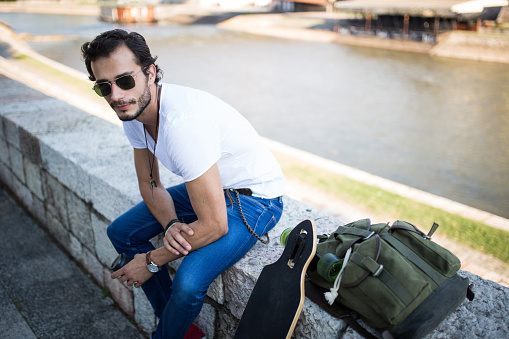 One man, holding coffee cup, sitting by the river.