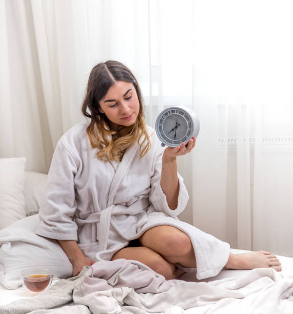 istock girl in the morning in bed with clock 683091740