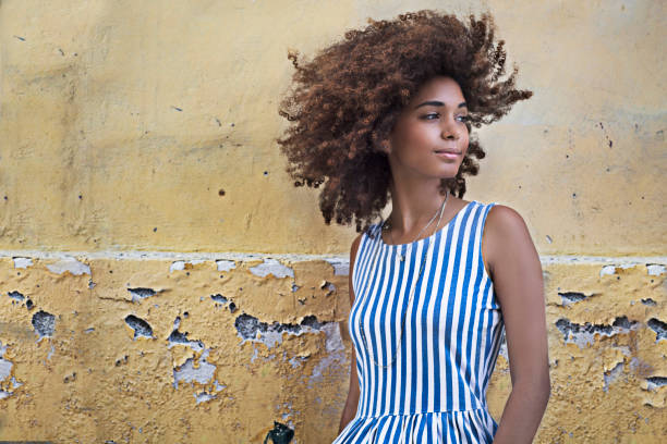 Beautiful woman standing against wall looking away